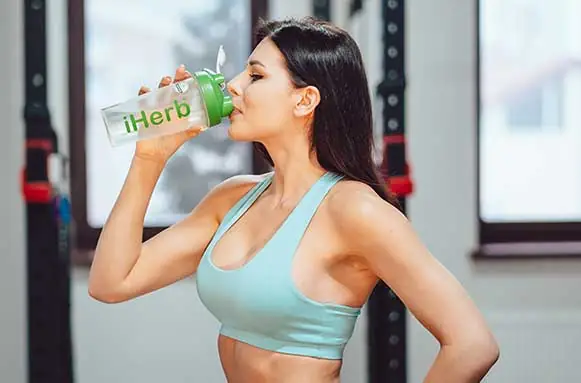 sportswoman-resting-drinking-water-stairs-gym